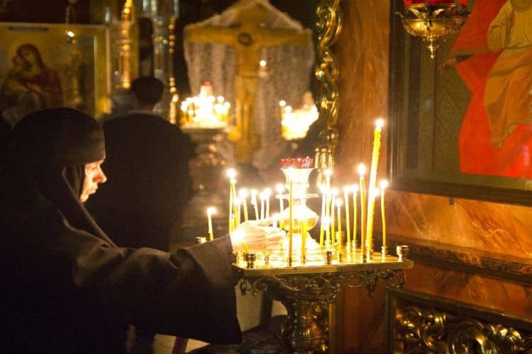 freira ortodoxa acendendo velas de adoração